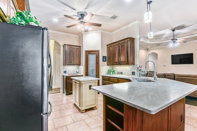 kitchen featuring stainless steel refrigerator, crown molding, a center island, and sink