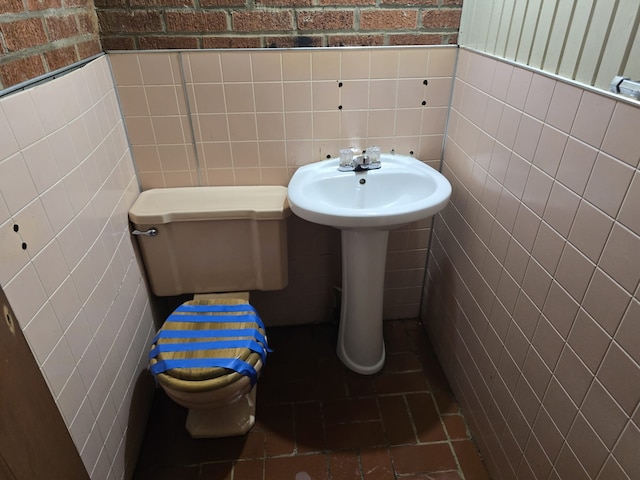 bathroom with toilet and tile walls