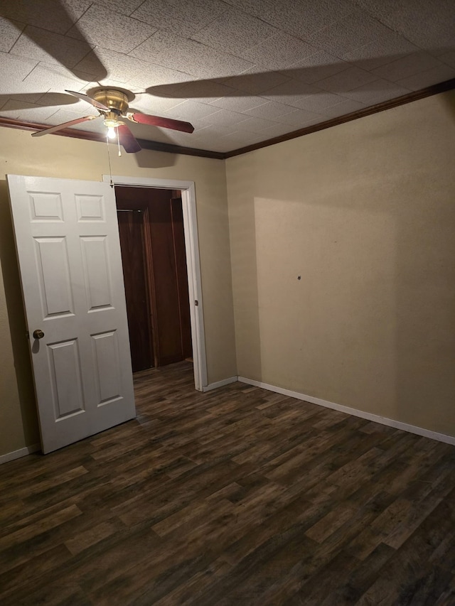 unfurnished bedroom with dark wood-type flooring, ceiling fan, ornamental molding, and a closet