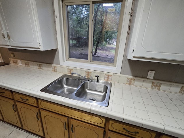 kitchen with white cabinetry, tile countertops, and sink