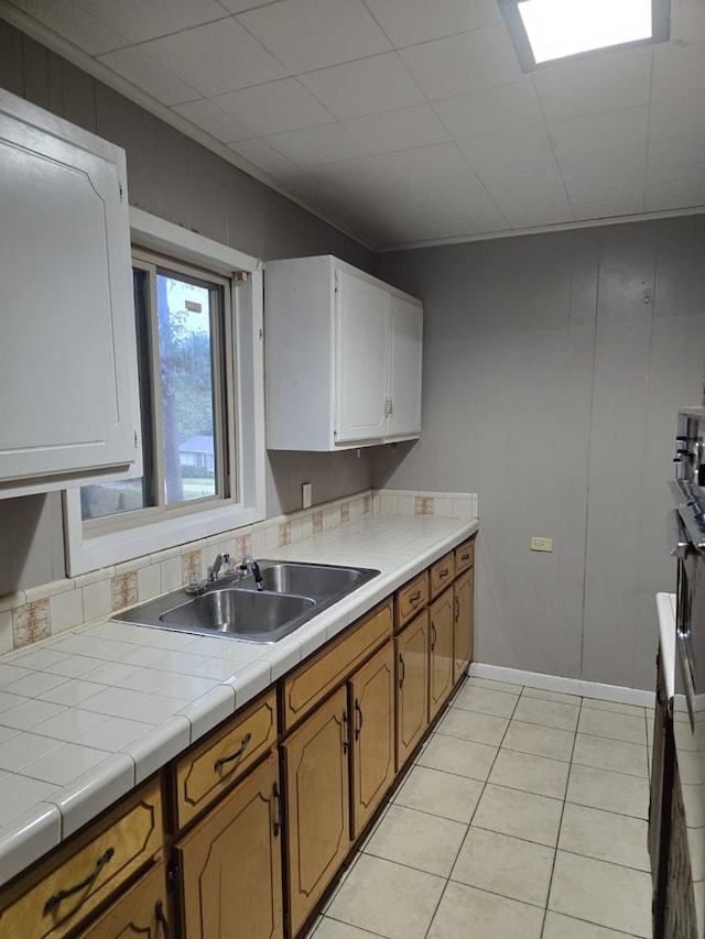 kitchen featuring sink, tile countertops, white cabinets, and light tile patterned flooring