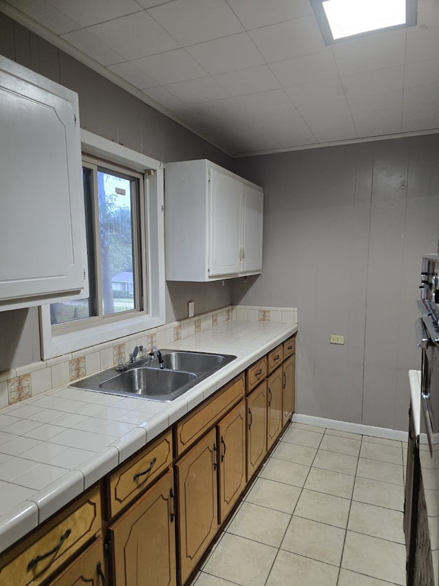 708 Walnut St, Atlanta, TX 75551 - kitchen with a sink, tile counters, light tile patterned floors, and brown cabinetry