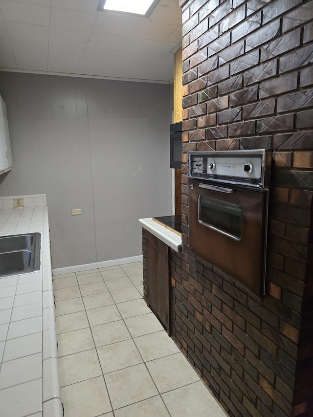 kitchen featuring sink, oven, and light tile patterned flooring