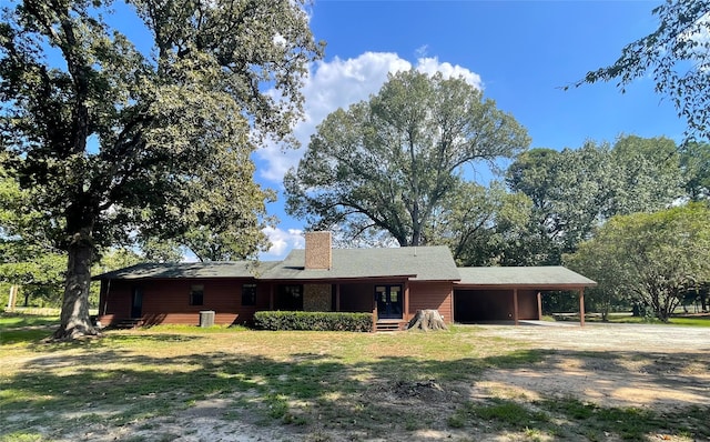 back of house with a lawn and a carport