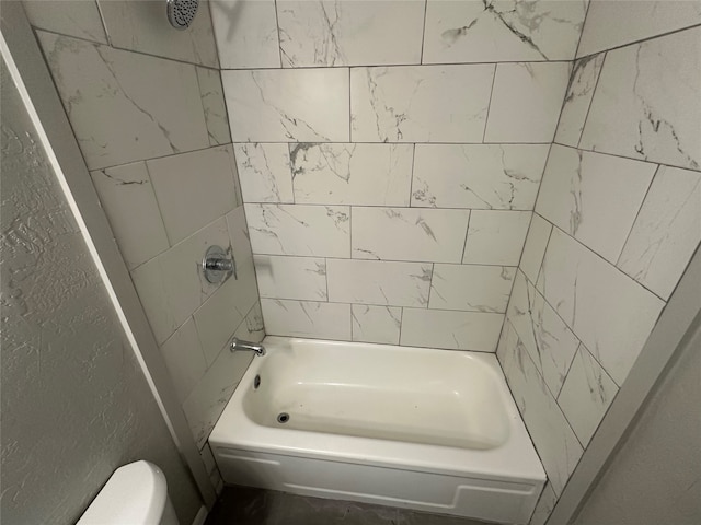 bathroom with toilet and tiled shower / bath