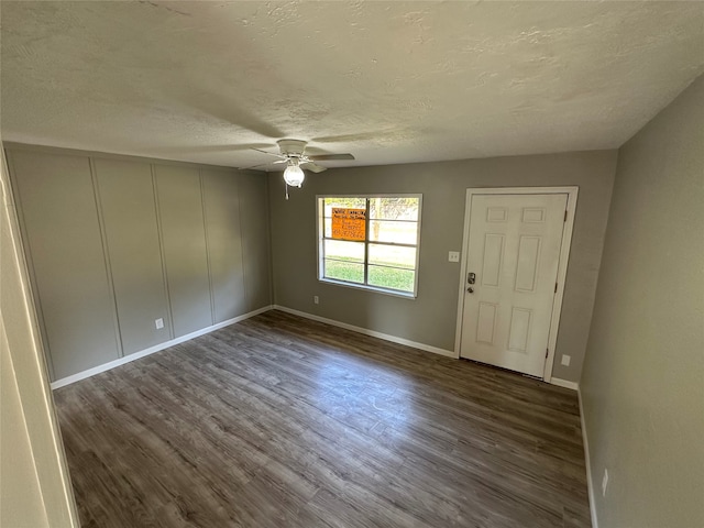 foyer entrance featuring a textured ceiling, ceiling fan, and dark wood-type flooring