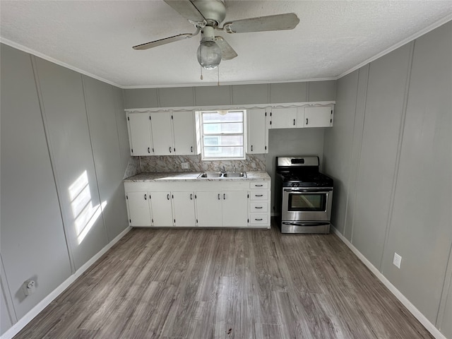 kitchen featuring sink, light hardwood / wood-style floors, white cabinetry, and stainless steel range with gas stovetop