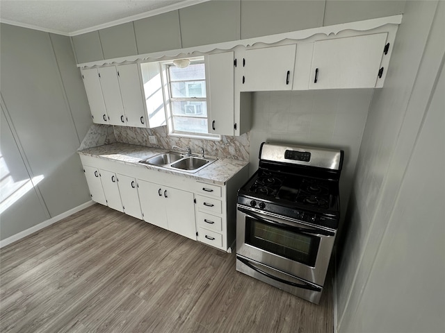 kitchen with white cabinets, sink, light hardwood / wood-style floors, and stainless steel gas range