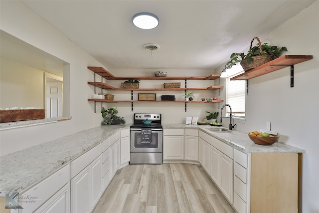 kitchen with white cabinets, sink, light stone countertops, stainless steel electric range oven, and light hardwood / wood-style floors