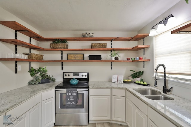 kitchen featuring light stone countertops, light wood-type flooring, stainless steel range with electric stovetop, sink, and white cabinetry