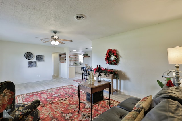 living room with a textured ceiling, light hardwood / wood-style flooring, ceiling fan, and sink