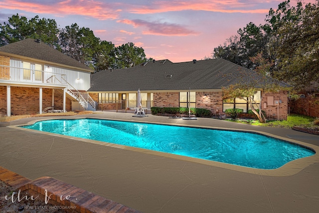 pool at dusk featuring a patio