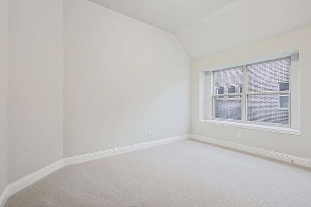 spare room featuring carpet and lofted ceiling