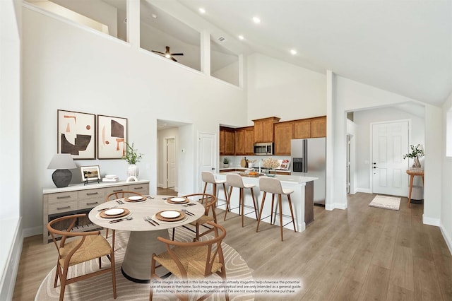 dining area featuring ceiling fan, high vaulted ceiling, and light wood-type flooring