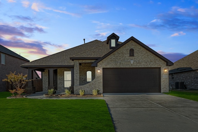 french country style house with a lawn, cooling unit, and a garage