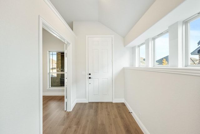 hall with light hardwood / wood-style flooring and vaulted ceiling