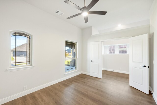 unfurnished bedroom featuring ceiling fan, wood-type flooring, and multiple windows