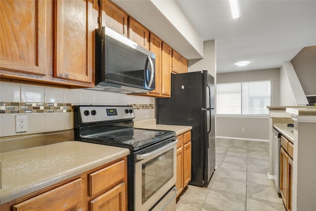 kitchen featuring brown cabinets, stainless steel appliances, tasteful backsplash, light countertops, and baseboards