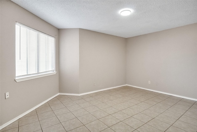 spare room with baseboards and a textured ceiling