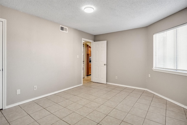 empty room with visible vents, a textured ceiling, and baseboards