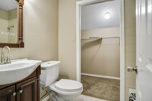 bathroom featuring a shower, a spacious closet, toilet, vanity, and baseboards