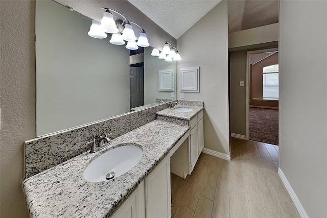 701 Squire Ct, Allen, TX 75002 - bathroom featuring double vanity, lofted ceiling, baseboards, wood finished floors, and a textured ceiling