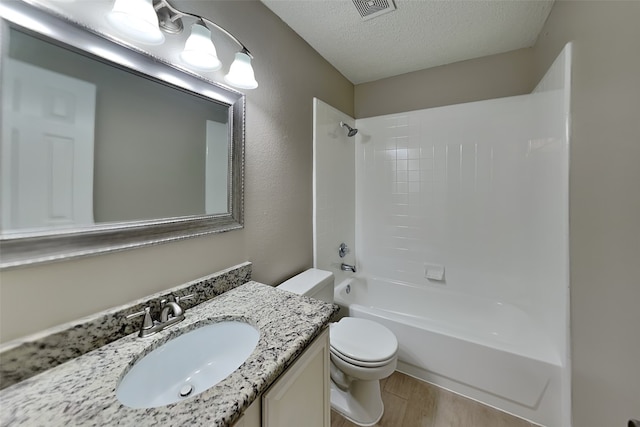 full bathroom featuring washtub / shower combination, hardwood / wood-style floors, a textured ceiling, toilet, and vanity