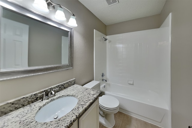 701 Squire Ct, Allen, TX 75002 - bathroom with a textured ceiling, toilet, vanity,  shower combination, and wood finished floors