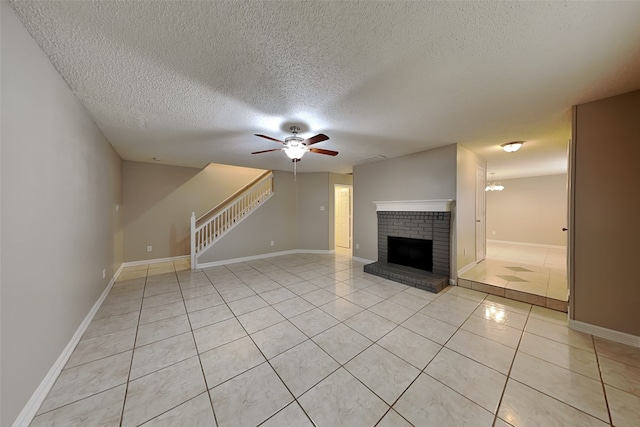 701 Squire Ct, Allen, TX 75002 - unfurnished living room featuring a textured ceiling, a ceiling fan, stairway, light tile patterned flooring, and a fireplace