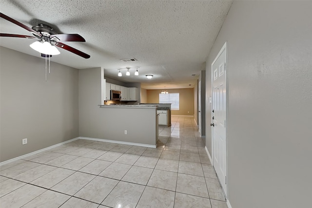701 Squire Ct, Allen, TX 75002 - kitchen with stainless steel microwave, a peninsula, ceiling fan, light tile patterned floors, and a textured ceiling