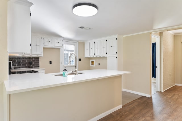 kitchen featuring sink, dark wood-type flooring, tasteful backsplash, kitchen peninsula, and white cabinets