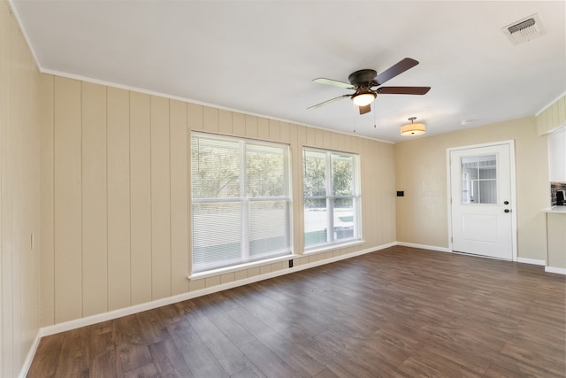 empty room with dark hardwood / wood-style floors, ceiling fan, and crown molding