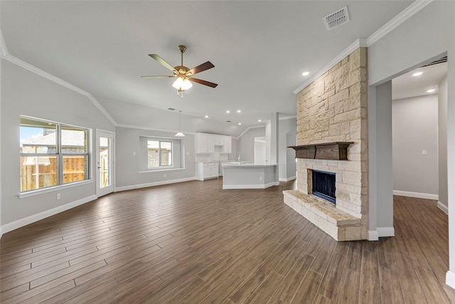 unfurnished living room with a stone fireplace, ornamental molding, dark hardwood / wood-style floors, and ceiling fan