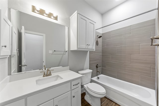 full bathroom with hardwood / wood-style flooring, tiled shower / bath, vanity, and toilet