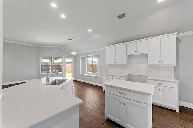 kitchen featuring lofted ceiling, sink, white cabinetry, an island with sink, and decorative light fixtures