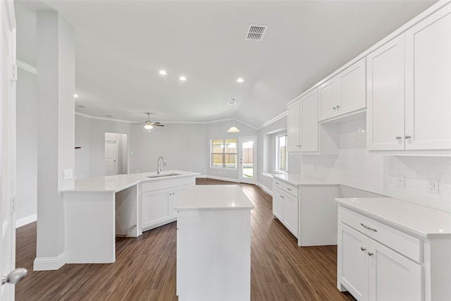 kitchen featuring sink, white cabinets, backsplash, a center island, and kitchen peninsula