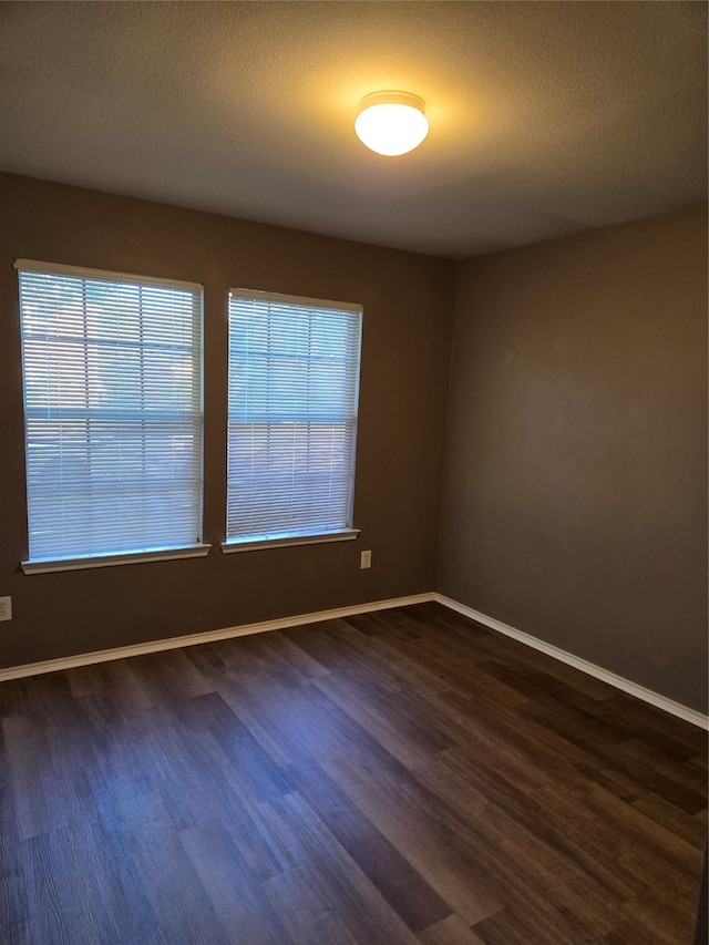 empty room featuring dark hardwood / wood-style flooring and a textured ceiling