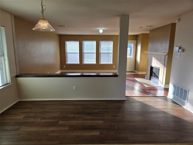 unfurnished living room featuring dark wood-type flooring and a tiled fireplace