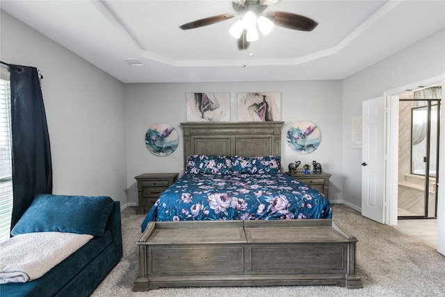 carpeted bedroom featuring a raised ceiling, multiple windows, and ceiling fan