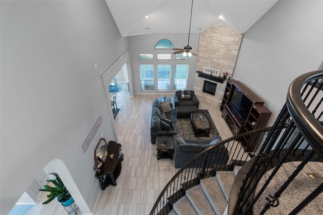 living room featuring ceiling fan, a fireplace, and high vaulted ceiling