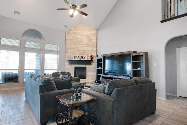 tiled living room with ceiling fan, a fireplace, and high vaulted ceiling