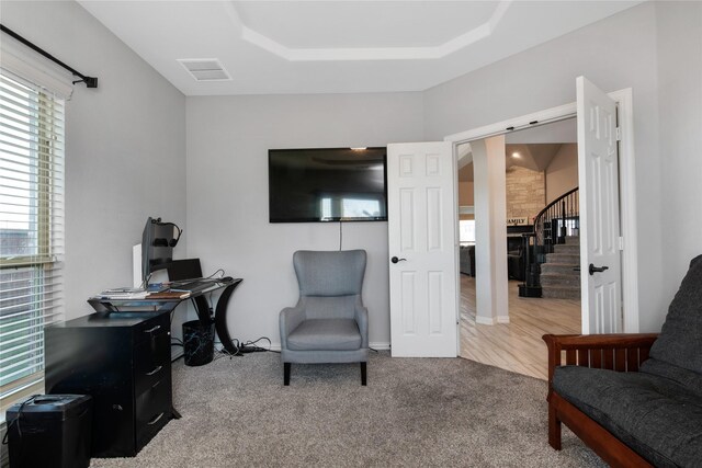 carpeted home office with a tray ceiling