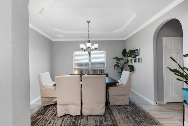 dining space with ornamental molding, a tray ceiling, and a chandelier