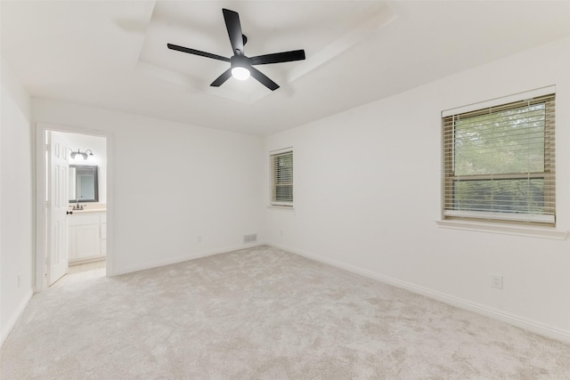 carpeted empty room with ceiling fan, a raised ceiling, and sink