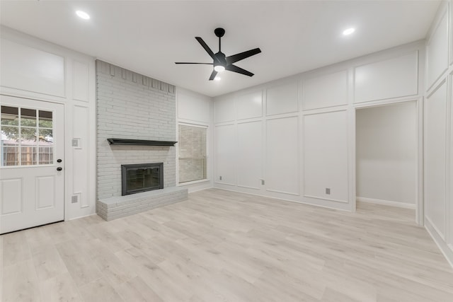 unfurnished living room with a fireplace, ceiling fan, and light wood-type flooring