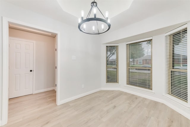 unfurnished dining area featuring an inviting chandelier and light hardwood / wood-style flooring