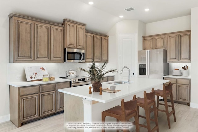 kitchen with an island with sink, stainless steel appliances, backsplash, and sink