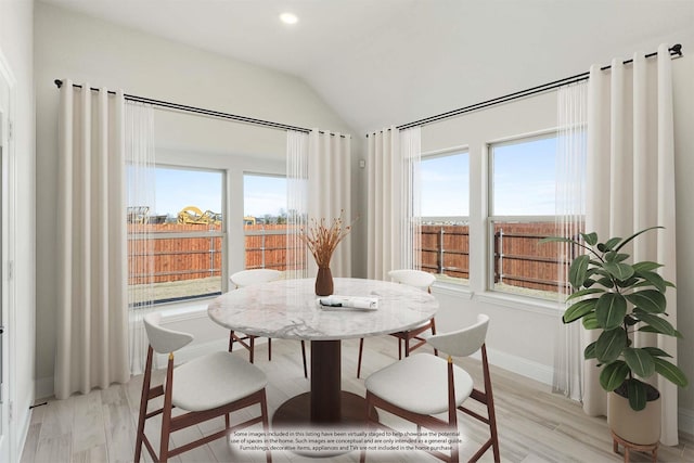 dining space with a healthy amount of sunlight, lofted ceiling, and light hardwood / wood-style floors