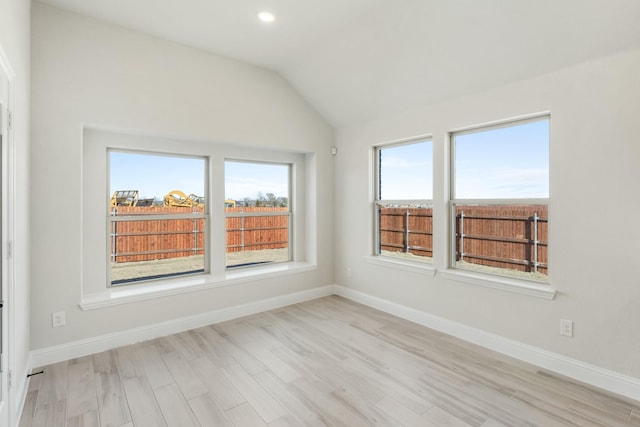 spare room with lofted ceiling and light hardwood / wood-style flooring