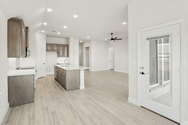 kitchen featuring ceiling fan, sink, an island with sink, and light hardwood / wood-style flooring